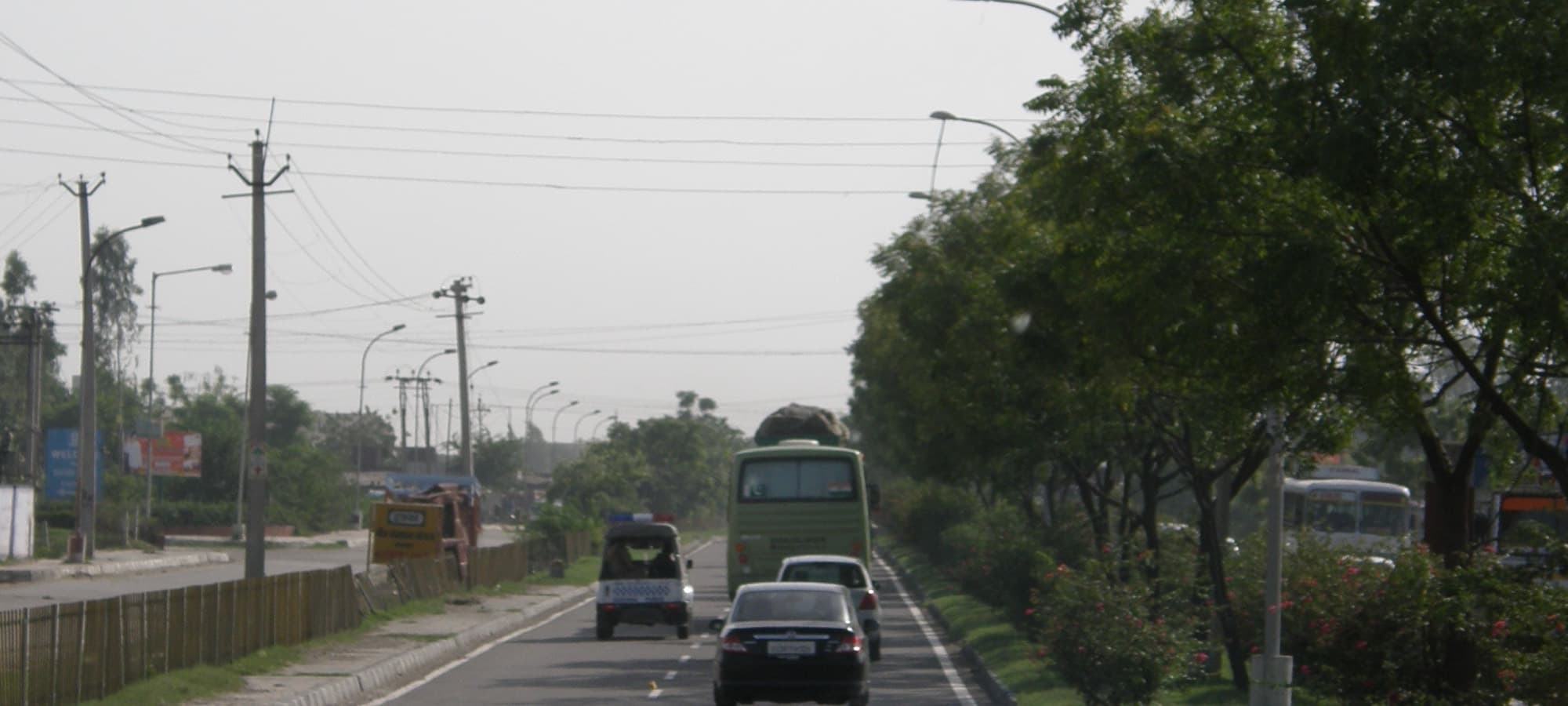 A highway on the outskirts of Delhi, with a bus and traffic in the middle distance.